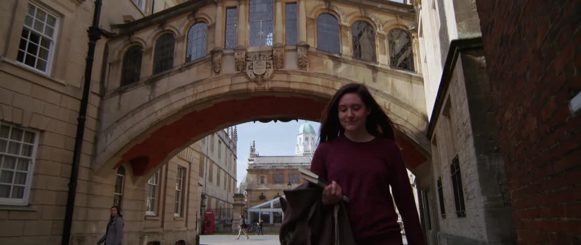 A female student is walking under the Hertford Bridge in Oxford England