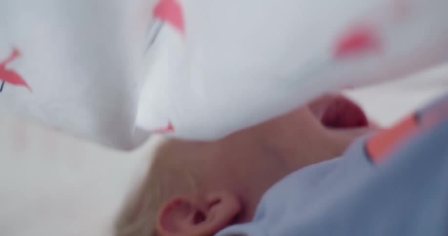 A little boy laughs under a sheet