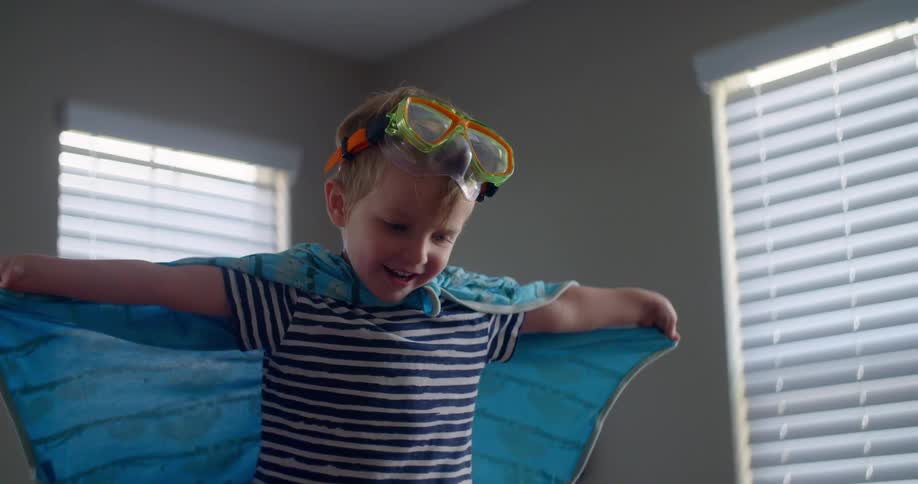 A young boy wears a cape and goggles playing
