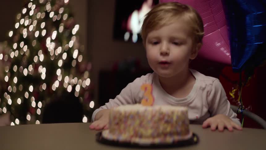 A little boy blows out the candle on his birthday cake and claps