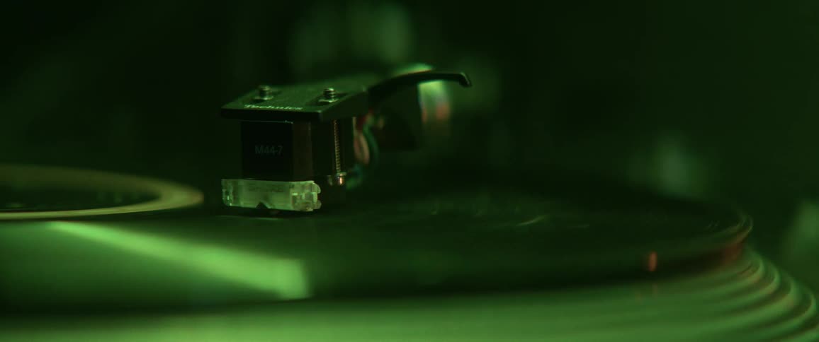 A vinyl record spinning atop a record player in a room with a light that repeatedly changes color