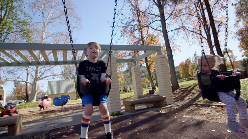 Hand pushing toddler in a bucket swing at a park