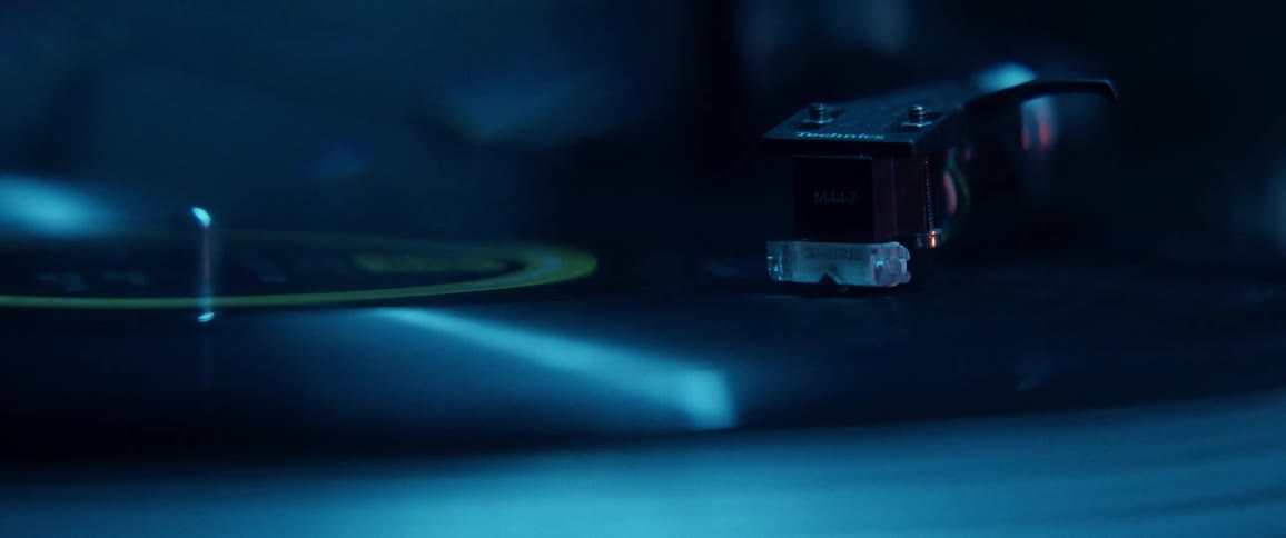 Record needle on spinning record under changing colored lighting