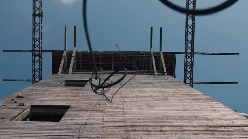 A rope falling off the side of a wooden wall with the sky above