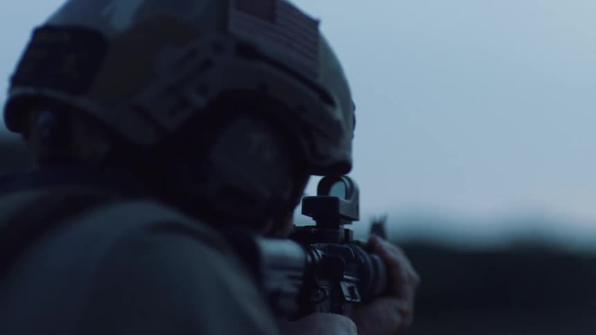 An american soldier fires rounds from a scoped rifle