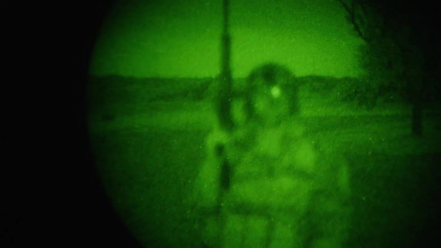 Out of focus night vision view of soldier holding gun