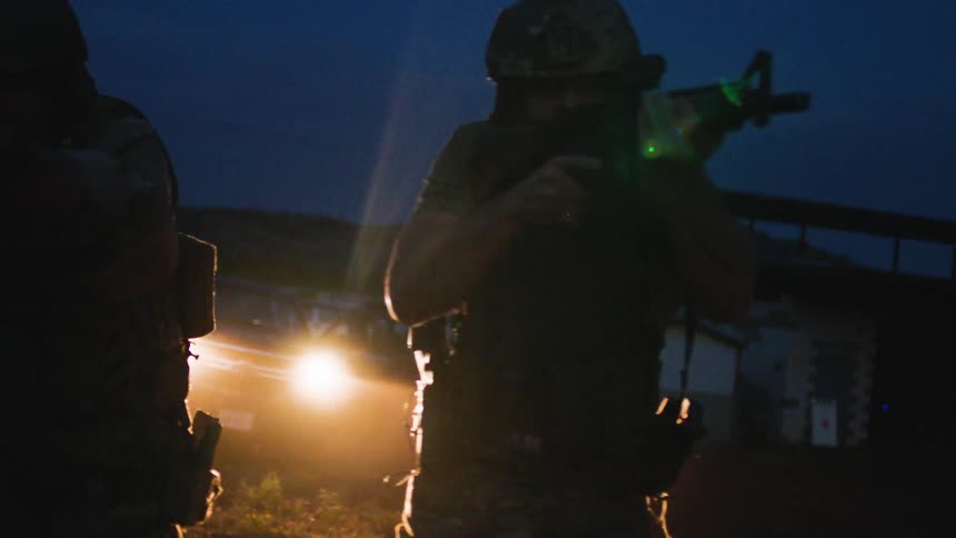 Soldiers aim their weapons as they approach their target