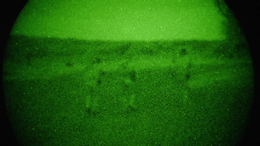 Extremely grainy green toned footage of three people walking