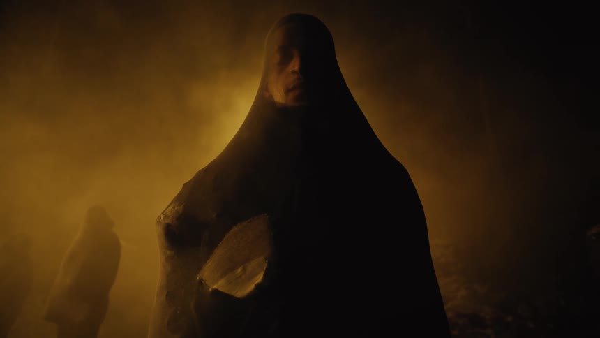 An actor stands on a dark stage