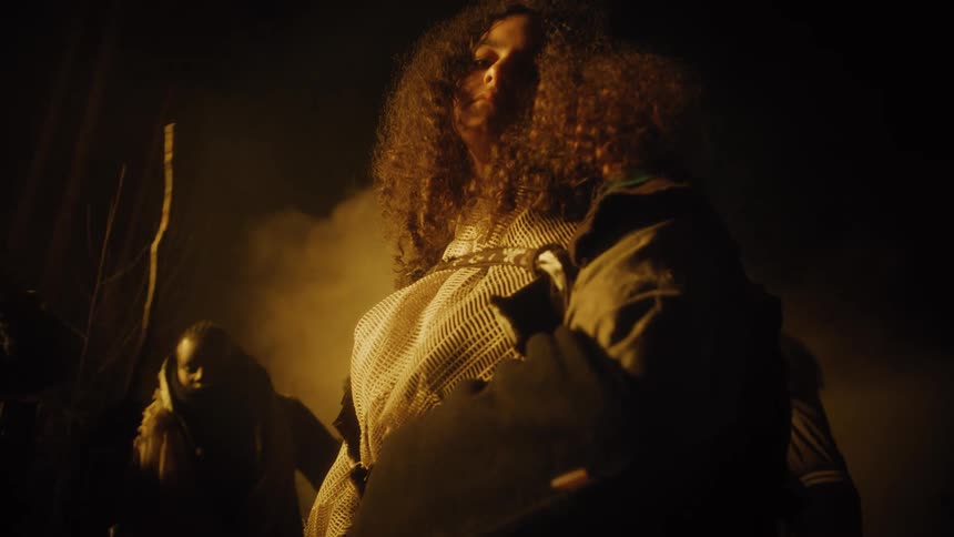 A woman in costume stands in front of people dancing