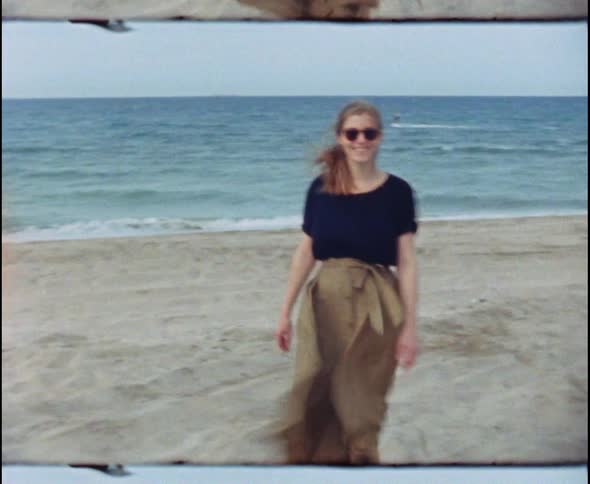 Vintage footage of young woman in dress on windy beach
