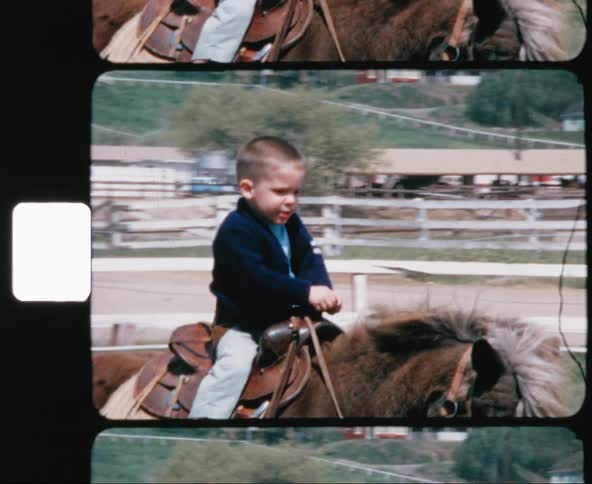 A white male child rides a pony in a fenced in field