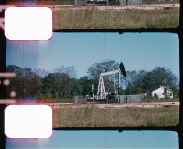 A fenced off oil pump moving up and down under a clear sky