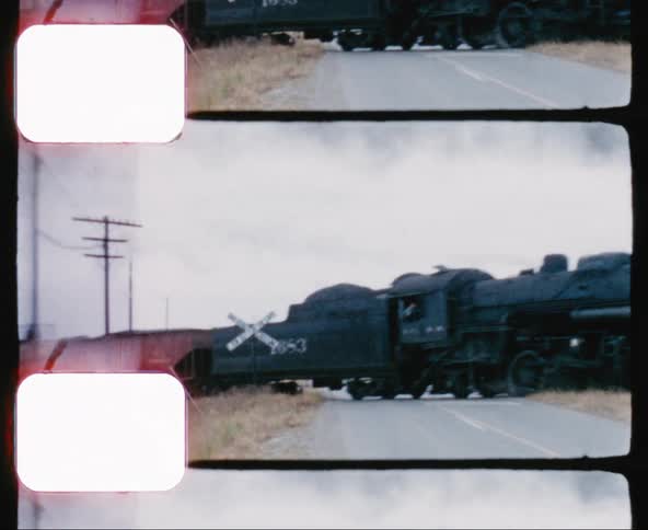 Freight train crosses over a road while a truck waits to cross