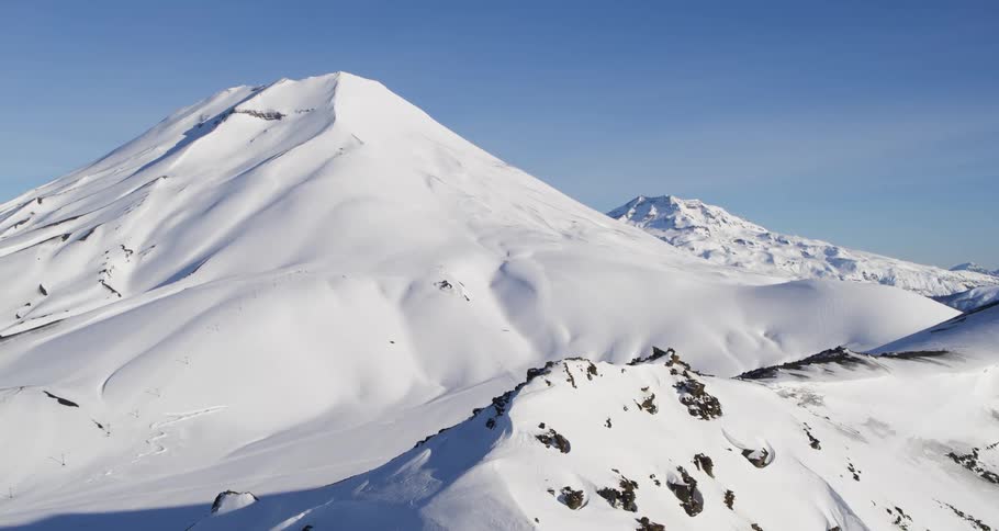 Aerial of snow covered mountain range and volcano