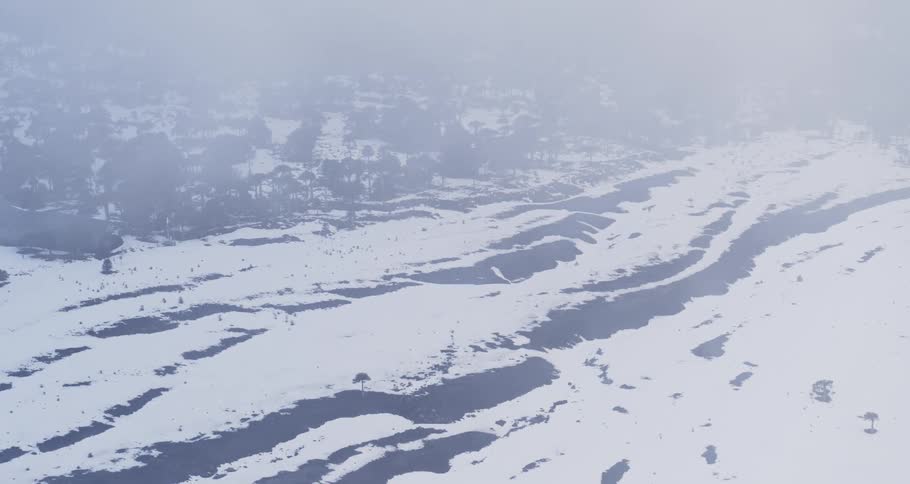 Drone push through clouds over a snowy lava field