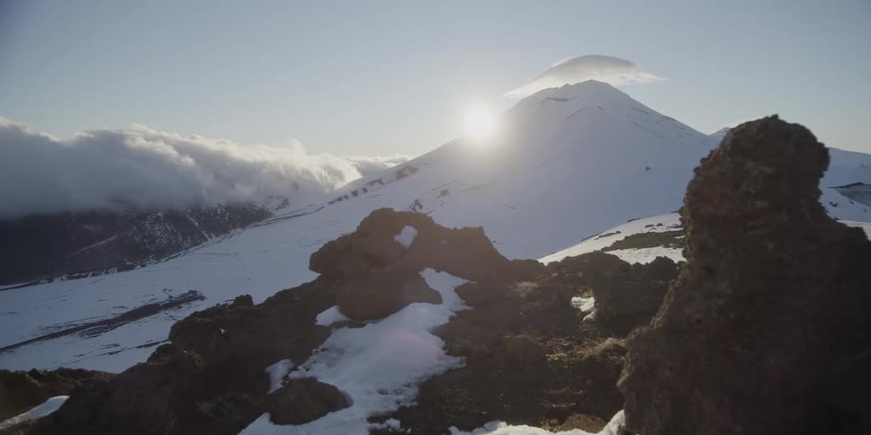 The sun over a snow covered volcanic peak