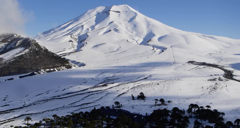Aerial push towards a massive snow covered volcano