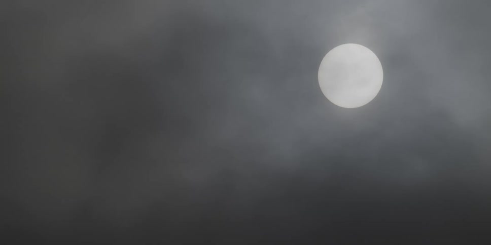The sun behind a cloudy sky