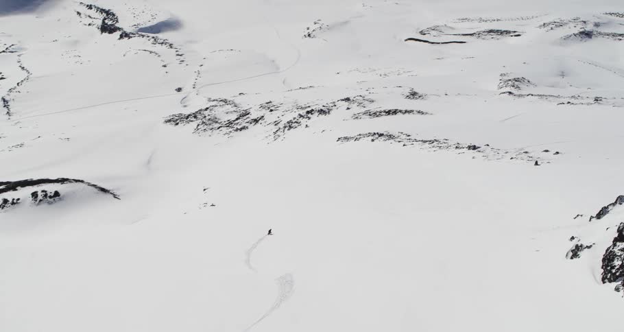Aerial as a person skis down a huge slope