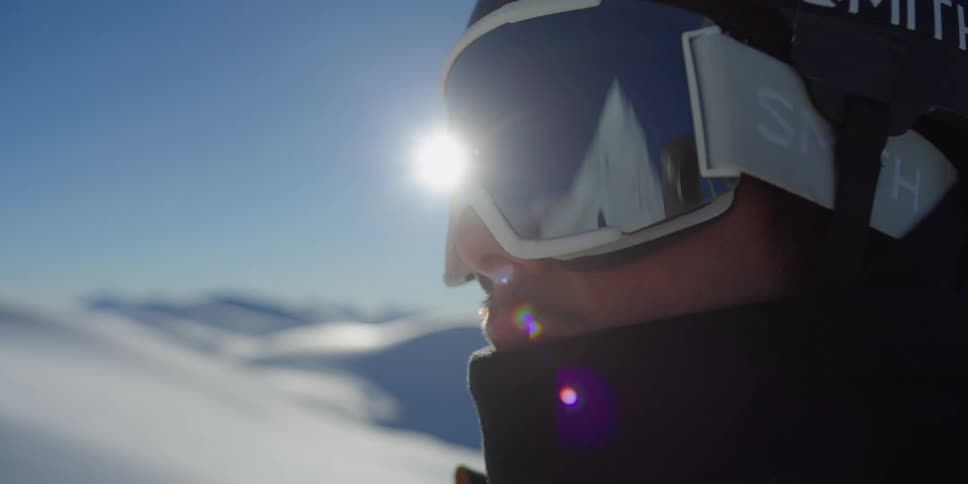 A skier looks at a mountain reflected in their goggles
