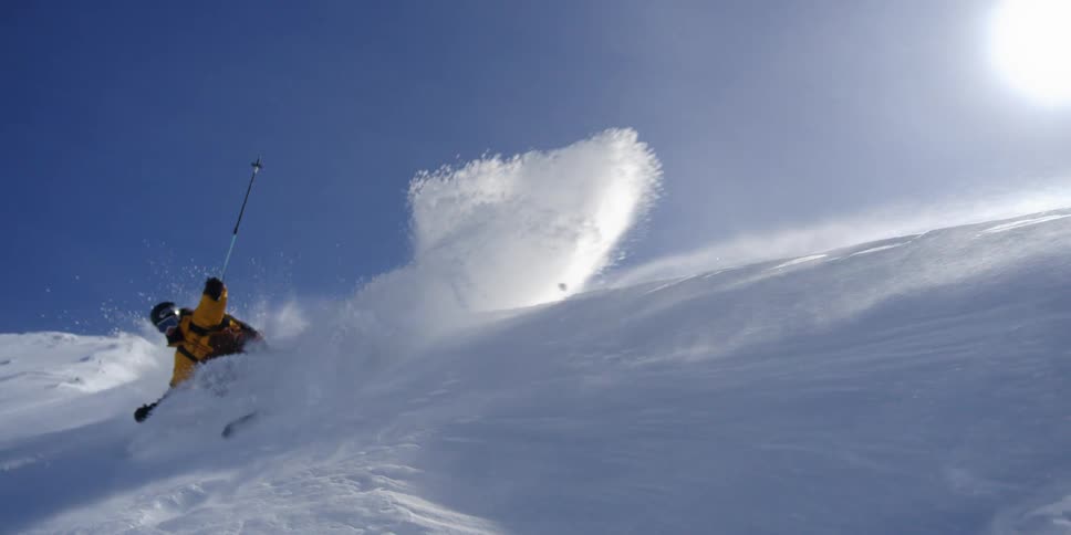 A skier sprays the camera with windblown snow