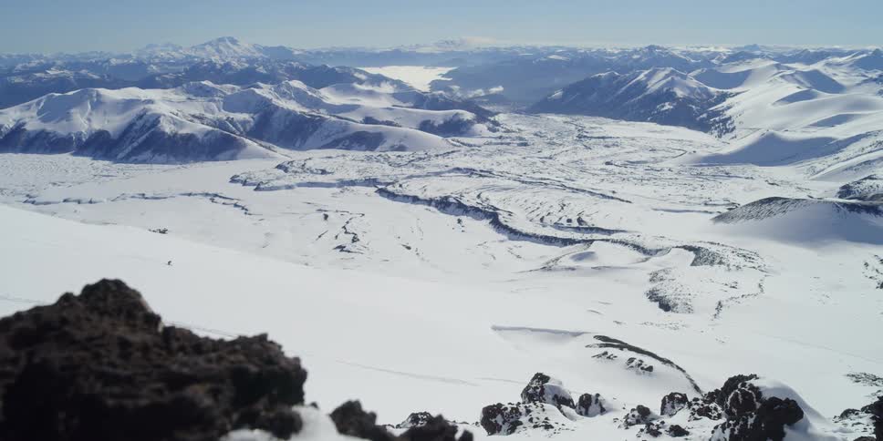 A skier skis down a big slope in front of an epic vista