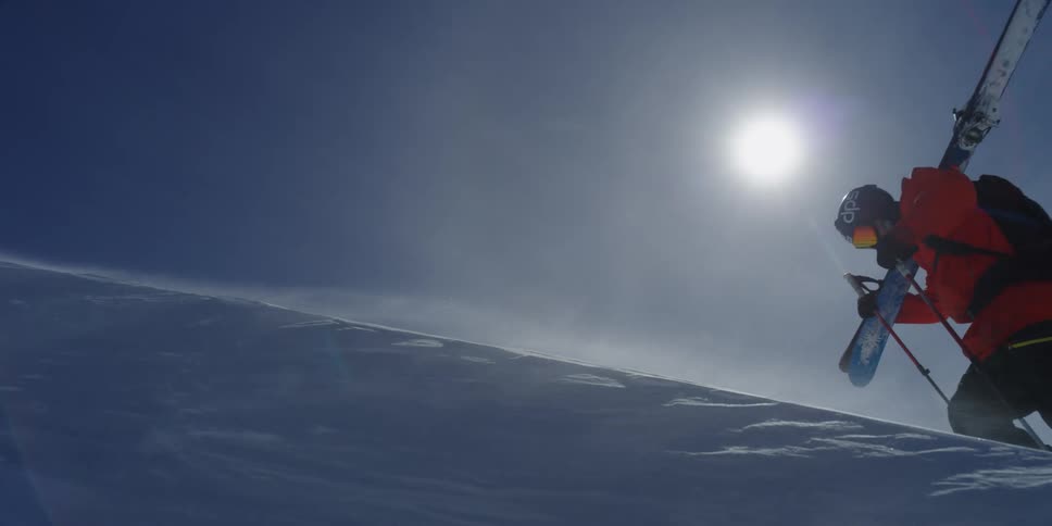 A skier fights wind while hiking through the snow