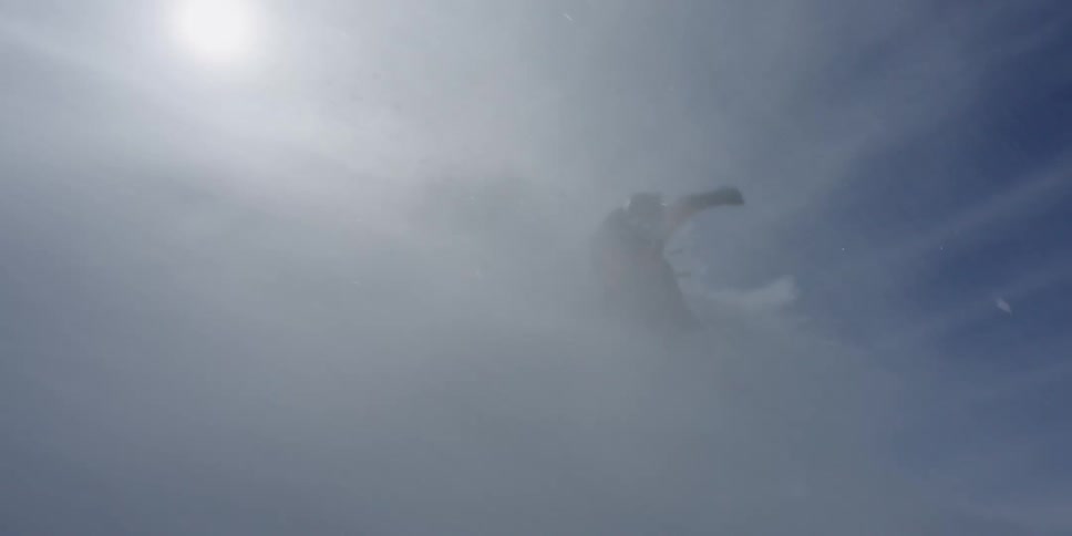 A skier skis through powder on a windy day