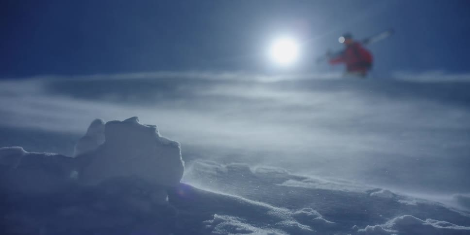 Wind blows across the landscape with a skier in the background