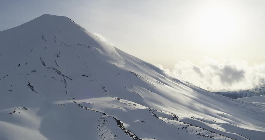 Aerial push towards a snowy volcano