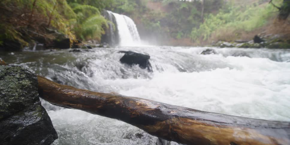 A waterfall feeds a river that runs into rapids
