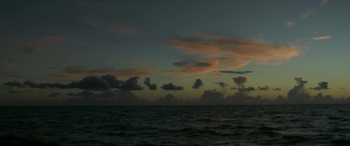 The sun sets over strong waves in the ocean