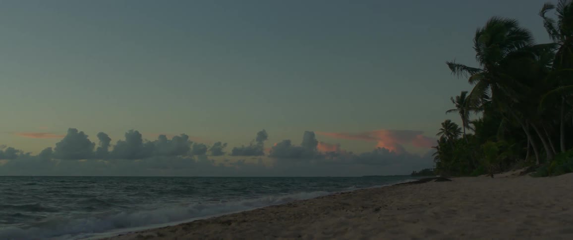 Waves crash onto a beach at sunrise
