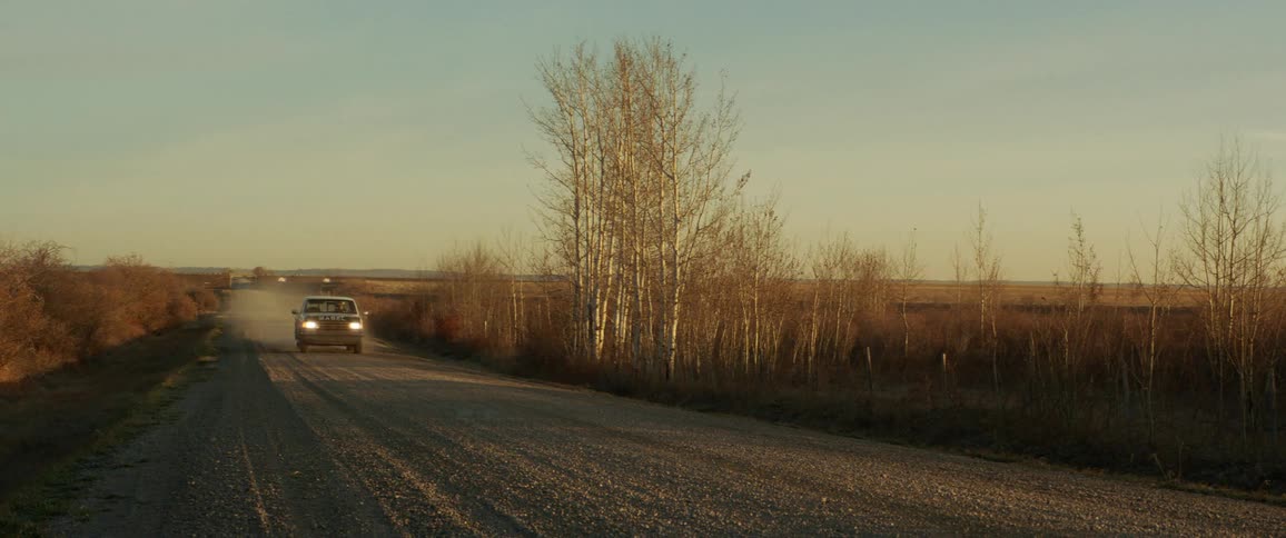 A man drives a truck down a dirt road