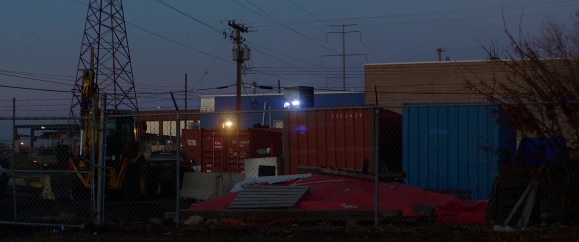 Shipping containers with a road with vehicles and electrical utility poles in the background