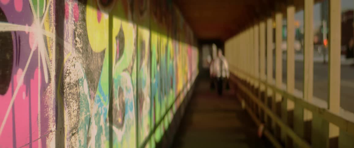 A man walks down a pathway with graffiti on the wall
