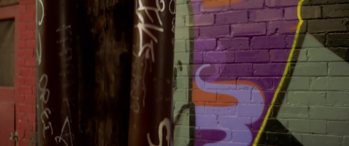 Words written on pole standing near graffiti decorated brick wall