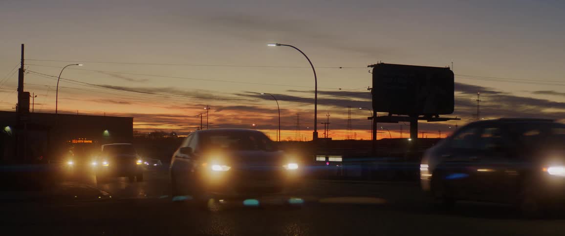 Cars driving down a road at sunset