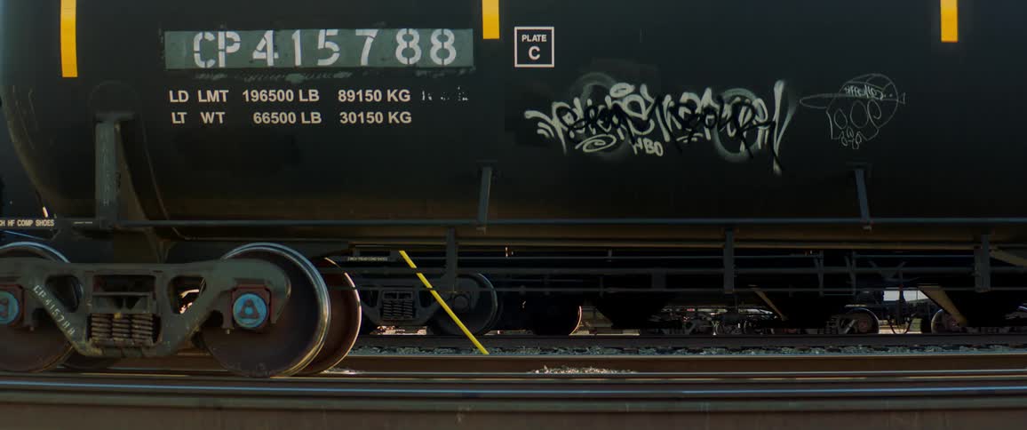 A train tanker car on the track with graffiti on its side