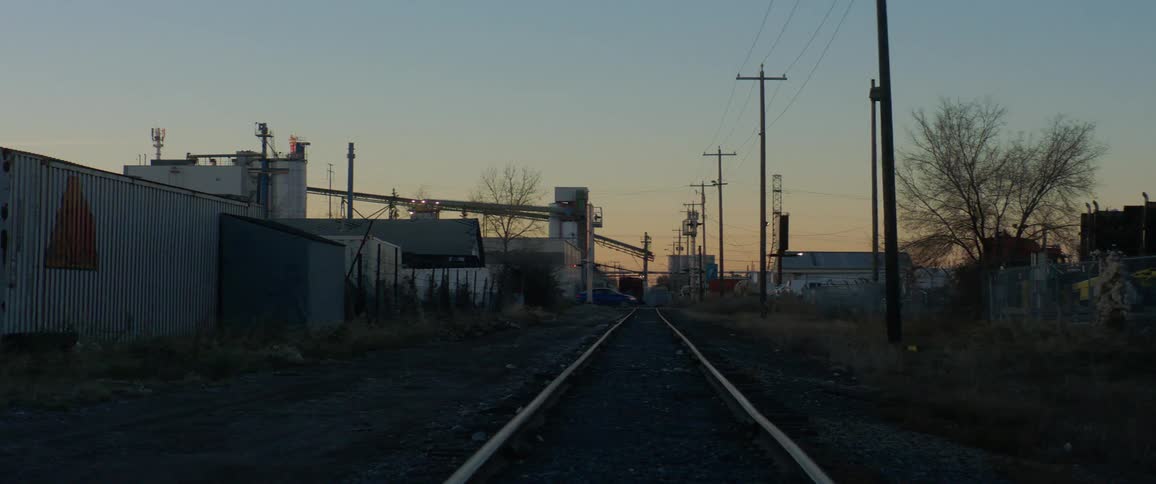 Train tracks through industrial area at dusk