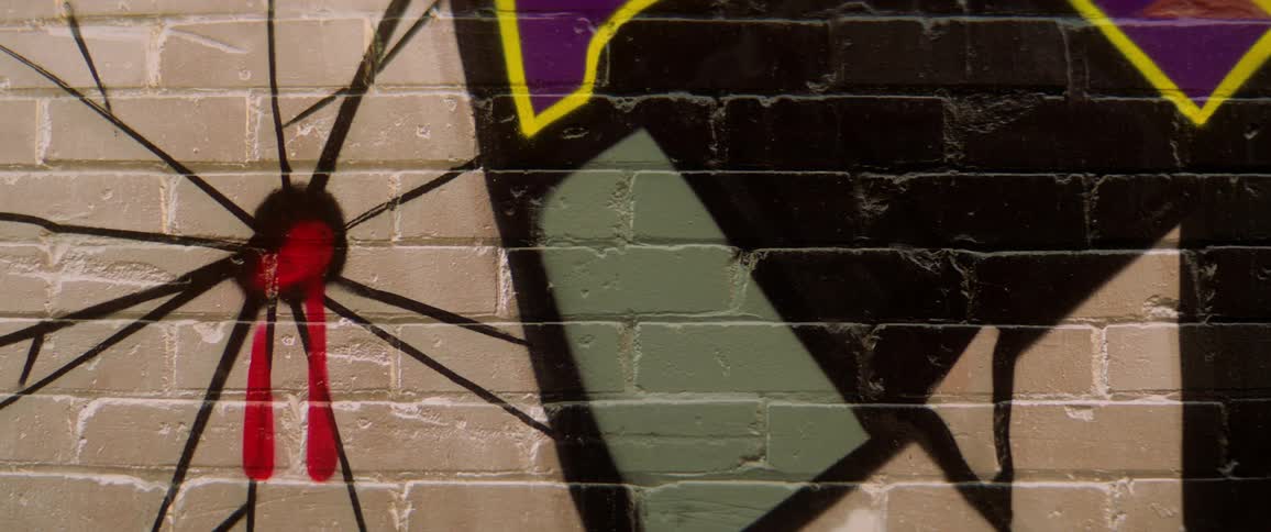 Black and other colored paints stands out against neutral painted brick wall