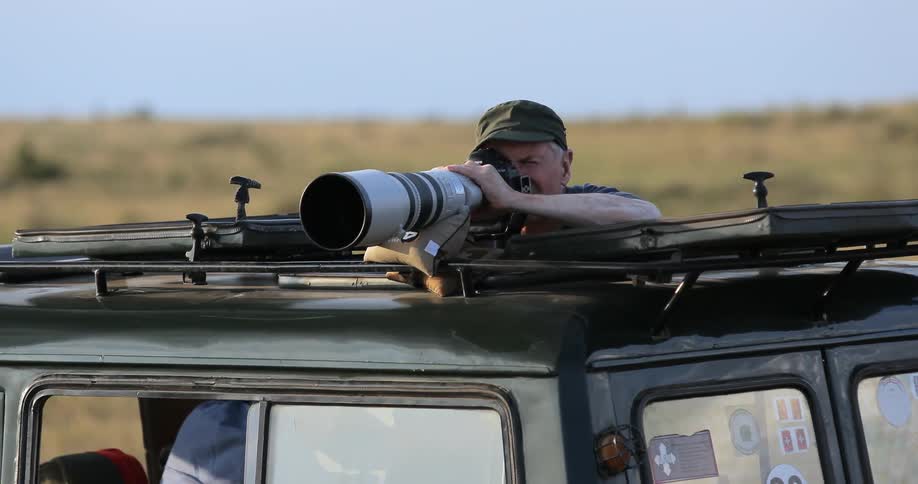 Man in a jeep taking pictures of wildlife