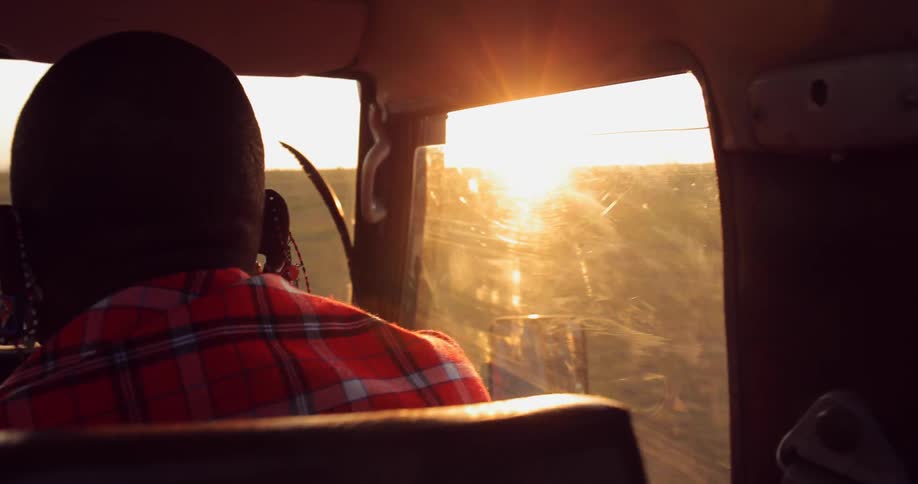 A man riding in a vehicle as the sun sets
