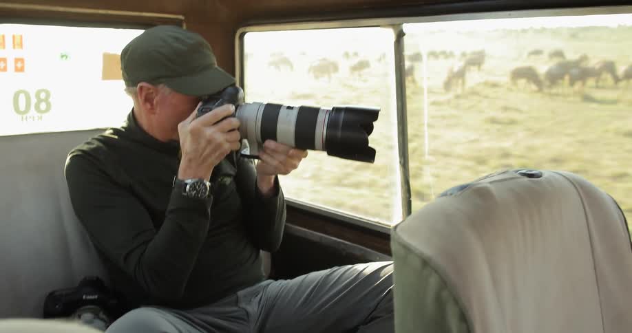 A man is taking photographs from the backseat of a vehicle