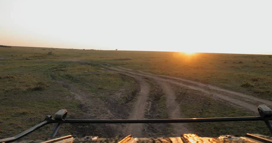 A truck drives down a path toward the sun