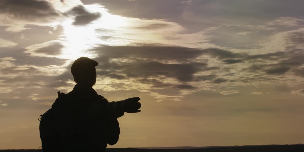 A man taking photographs as the sun begins to set