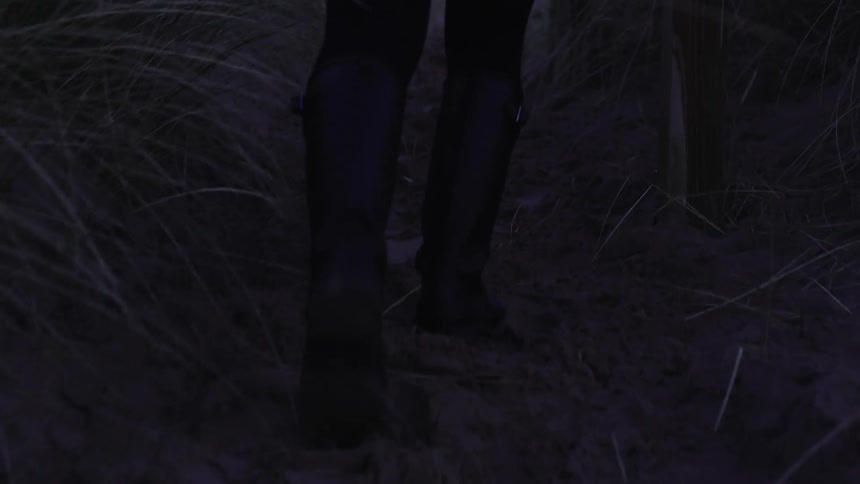 A person walks down a muddy path with straw on the side