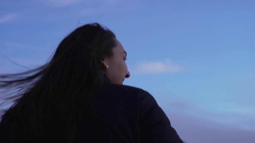 Woman ascends stairs and looks around smilingly on the beach