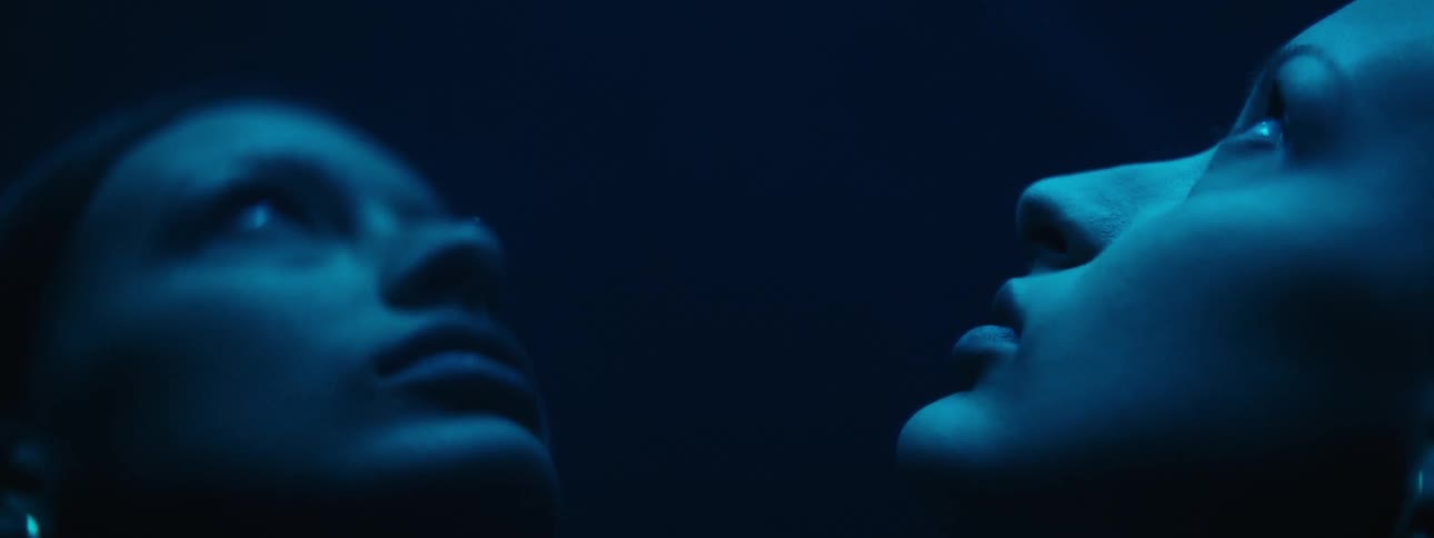 A white woman stands and looks up as her face is reflected in a mirror